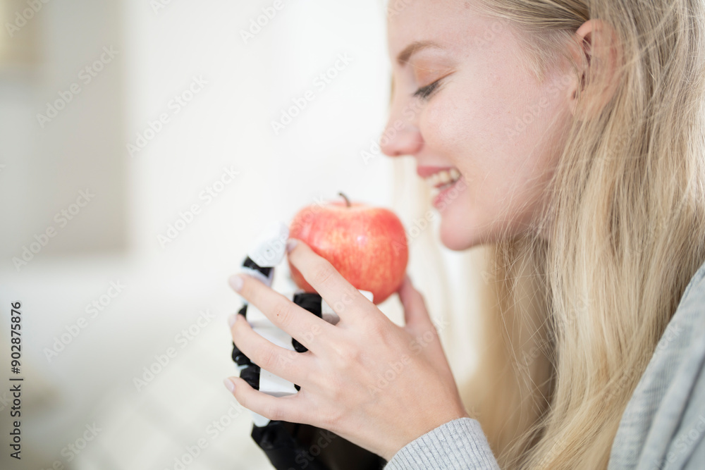 A young woman is using a robotic prosthetic arm attached to her body. She controls her hand to pick up objects food fruits and apples. The woman tries to control the smart arm in her home. A young woman is using a robotic prosthetic arm attached to her body. She controls her hand to pick up objects food fruits and apples. The woman tries to control the smart arm in her home.