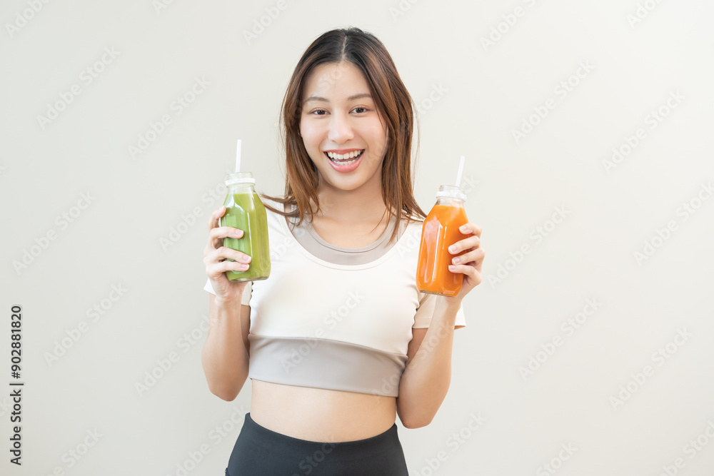 Orange, green detox juice, smile asian young woman hand holding bottle of vegetable juice, carrot smoothie for diet, girl drinking healthy meal food for weight loss, standing isolated on background Orange, green detox juice, smile asian young woman hand holding bottle of vegetable juice, carrot smoothie for diet, girl drinking healthy meal food for weight loss, standing isolated on background