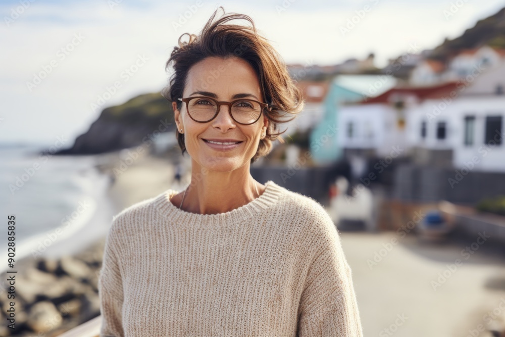 Fototapeta premium Portrait of a satisfied woman in her 40s wearing a chic cardigan isolated in picturesque seaside village