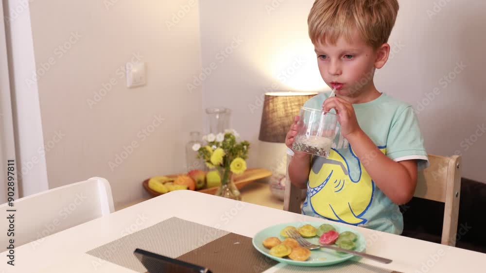 Caucasian Boy Enjoys Colorful Treats While Standing in Kitchen at Home Caucasian Boy Enjoys Colorful Treats While Standing in Kitchen at Home