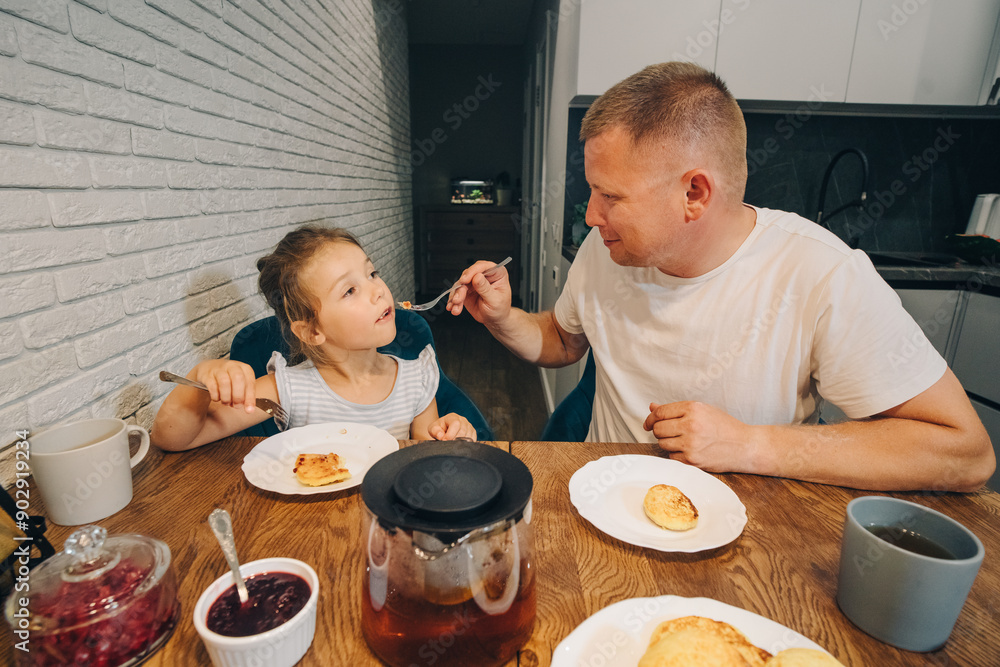 A Father and his Daughter are Happily Enjoying Breakfast Together and Bonding Over Food. A happy family enjoys the moments of eating food together at home. A Father and his Daughter are Happily Enjoying Breakfast Together and Bonding Over Food. A happy family enjoys the moments of eating food together at home.