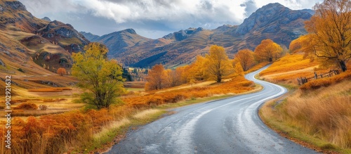 Scenic rural road winding through a stunning golden autumn mountain landscape with a natural background perfect for a copy space image