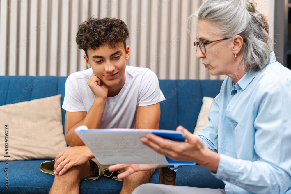 © Maria Vitkovska - Senior female psychologist showing treatment plan to teenage boy during therapy session