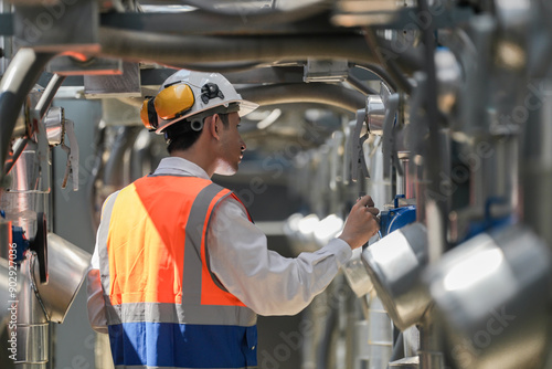 Engineers inspect gas and water pipes for power and cooling in industrial and building systems. workers in safety gear work seriously in oil and gas refining plant with pipes connecting to machinery.