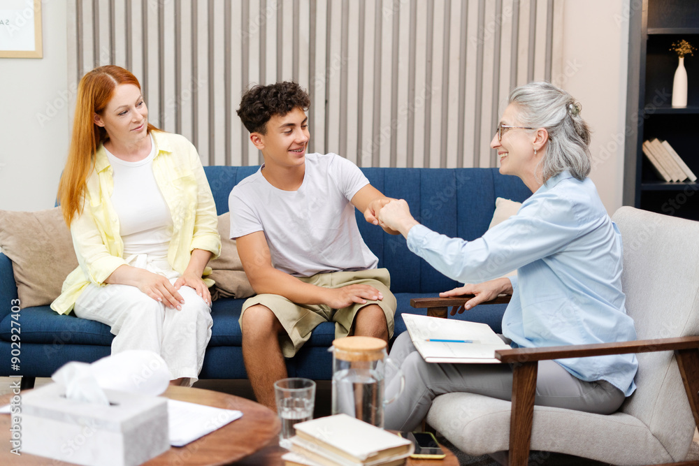 Fototapeta premium Happy teenage boy giving fist bump with therapist after successful therapy session