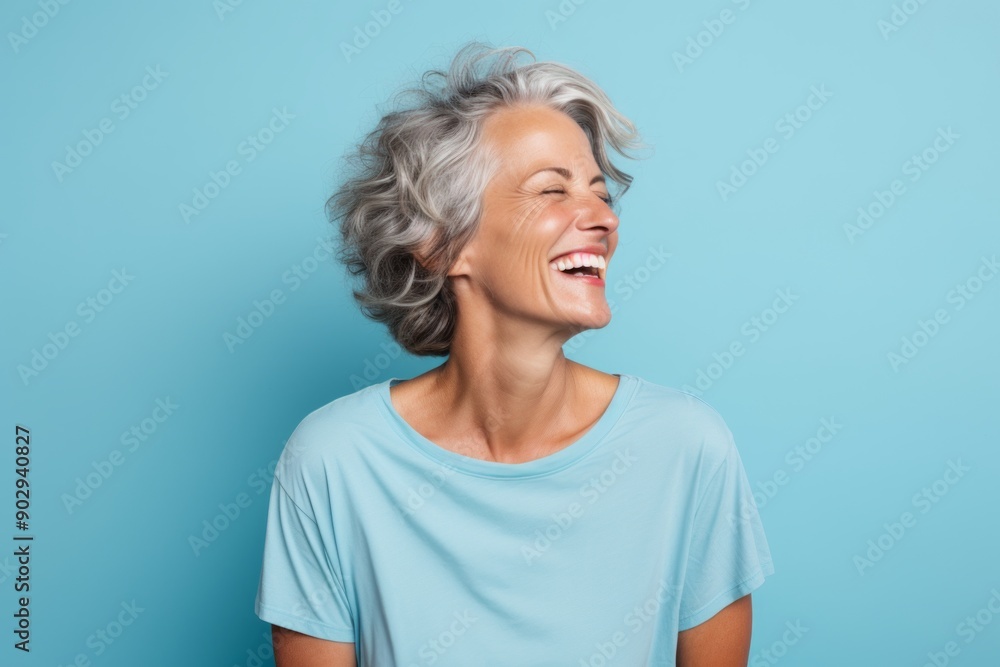 Portrait of a joyful woman in her 50s sporting a vintage band t-shirt in pastel blue background Portrait of a joyful woman in her 50s sporting a vintage band t-shirt in pastel blue background