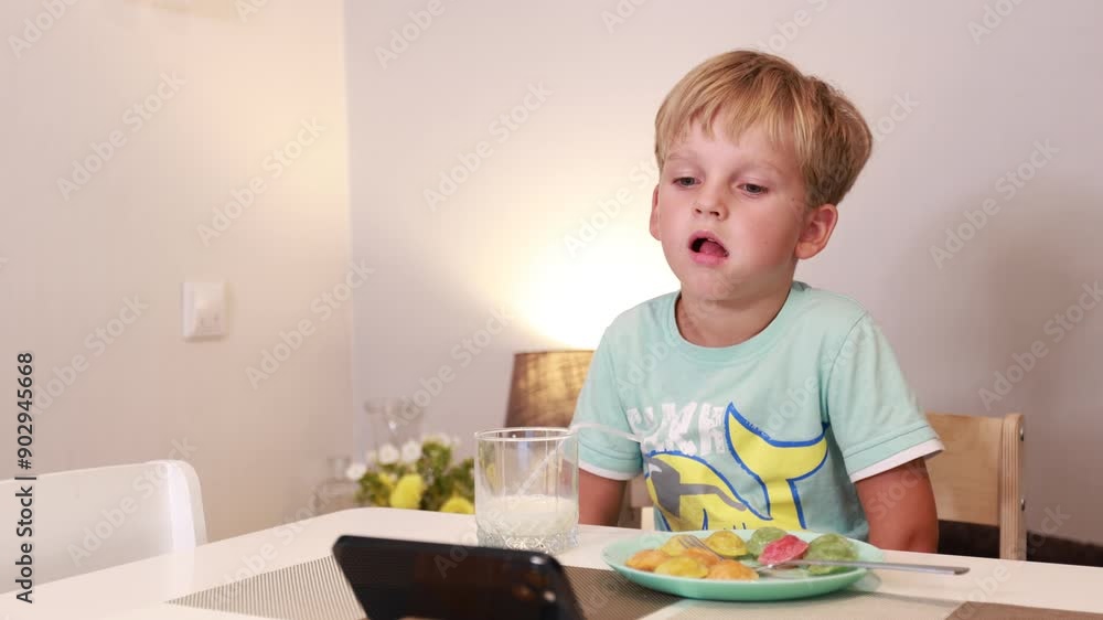 Caucasian Boy Enjoying a Delicious Meal in the Kitchen While Watching a Screen Caucasian Boy Enjoying a Delicious Meal in the Kitchen While Watching a Screen