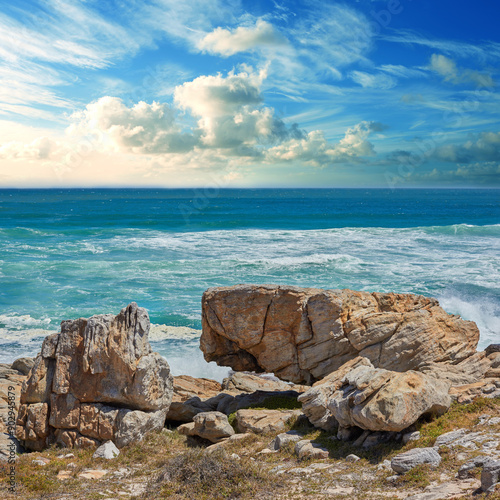 Rocks, ocean and water in nature outdoor for travel destination, coat environment and natural beauty. Blue sky, beach and scenery for seaside peace, tourism journey with adventure location of view