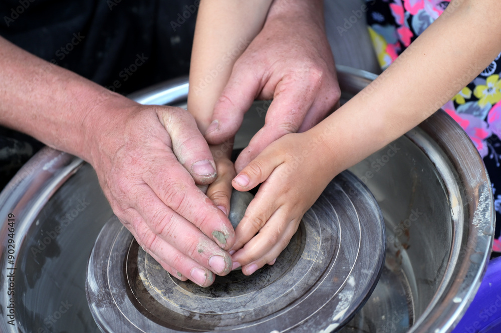 Potter helps to the child at a pottery master class.