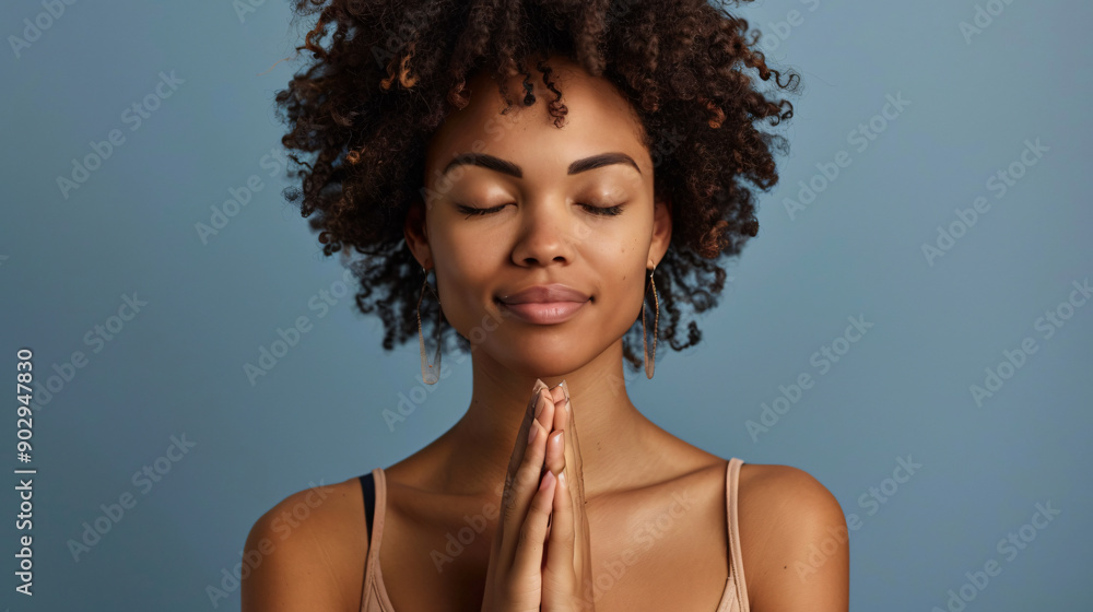 Serene young woman meditates with her eyes closed and hands clasped together Serene young woman meditates with her eyes closed and hands clasped together