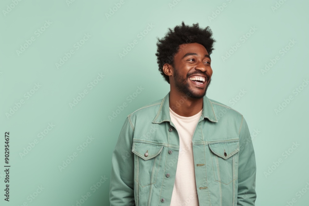 Portrait of a happy afro-american man in his 30s sporting a rugged denim jacket isolated in pastel green background Portrait of a happy afro-american man in his 30s sporting a rugged denim jacket isolated in pastel green background