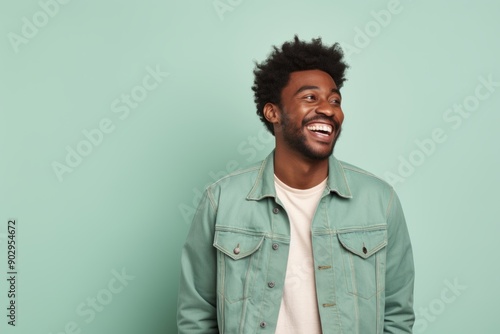 Portrait of a happy afro-american man in his 30s sporting a rugged denim jacket isolated in pastel green background