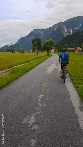 Rear view of man cycling along the Alpe Adria trail in Friuli-Venezia Giulia, Italy, Europe. Scenic mountain road, surrounded by nature beauty and remote village in Northern Italy