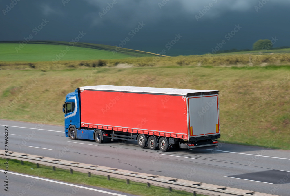 Blue Cargo Semi-Truck with Red Enclosed Trailer on Highway Blue Cargo Semi-Truck with Red Enclosed Trailer on Highway