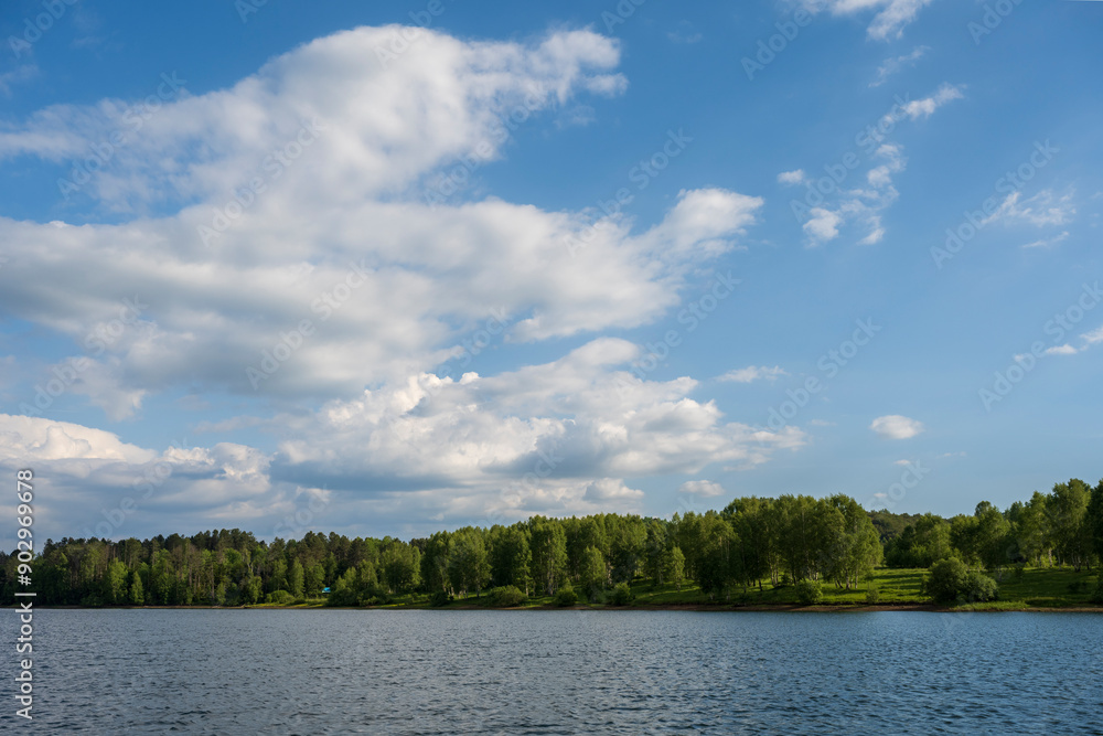 White puffy clouds and blue sky above Vlasina Lake. White cumulus clouds and a blue sky with sun rays. Beautiful semi-artificial lake in Southeast Serbia. White puffy clouds and blue sky above Vlasina Lake. White cumulus clouds and a blue sky with sun rays. Beautiful semi-artificial lake in Southeast Serbia.
