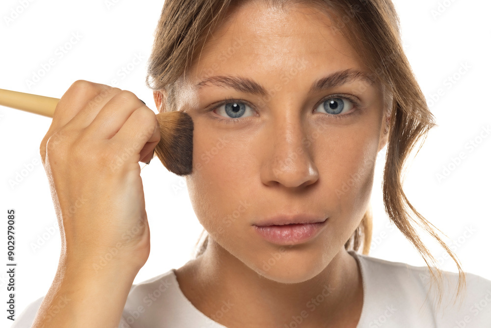 Portrait of a beautiful young woman applying makeup foundation on a white background Portrait of a beautiful young woman applying makeup foundation on a white background