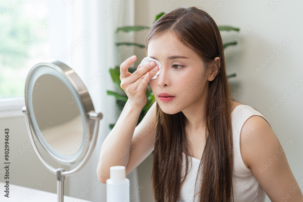 Remove makeup, attractive asian young woman, girl looking into mirror, hand holding cotton pad, apply facial wipe cleaning on her skin face, essence or lotion for treatment, skin care routine at home. Remove makeup, attractive asian young woman, girl looking into mirror, hand holding cotton pad, apply facial wipe cleaning on her skin face, essence or lotion for treatment, skin care routine at home.