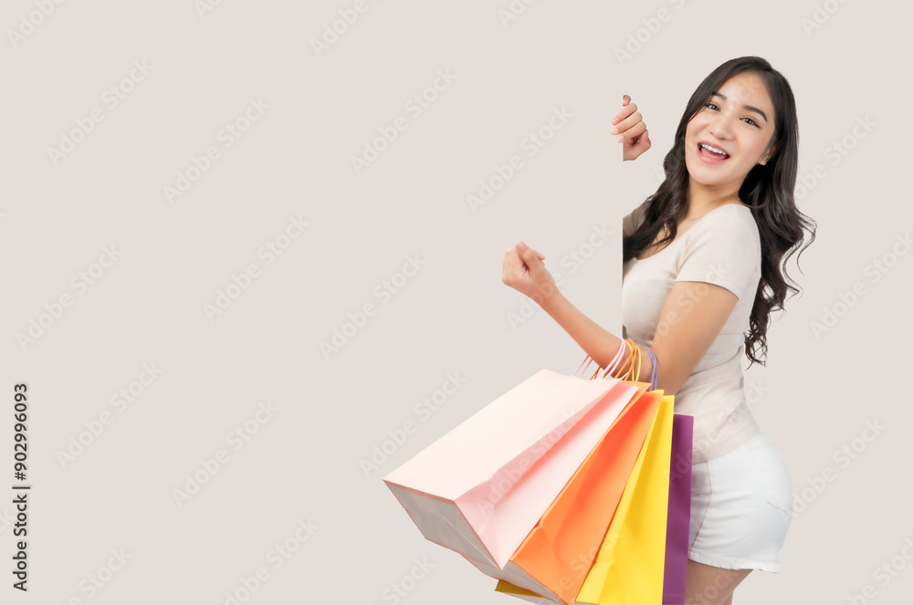 A cheerful young Asian woman enjoying a successful shopping trip, holding colorful shopping bags against a neutral background She wear shorts in summer time copy space for insert text or advertisement A cheerful young Asian woman enjoying a successful shopping trip, holding colorful shopping bags against a neutral background She wear shorts in summer time copy space for insert text or advertisement