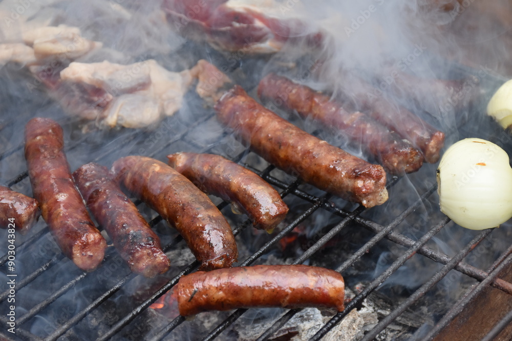 Sausages on a smoking grill, close-up. Sausage BBQ on wood ember, smoking. Barbecue, smoke background Sausages on a smoking grill, close-up. Sausage BBQ on wood ember, smoking. Barbecue, smoke background