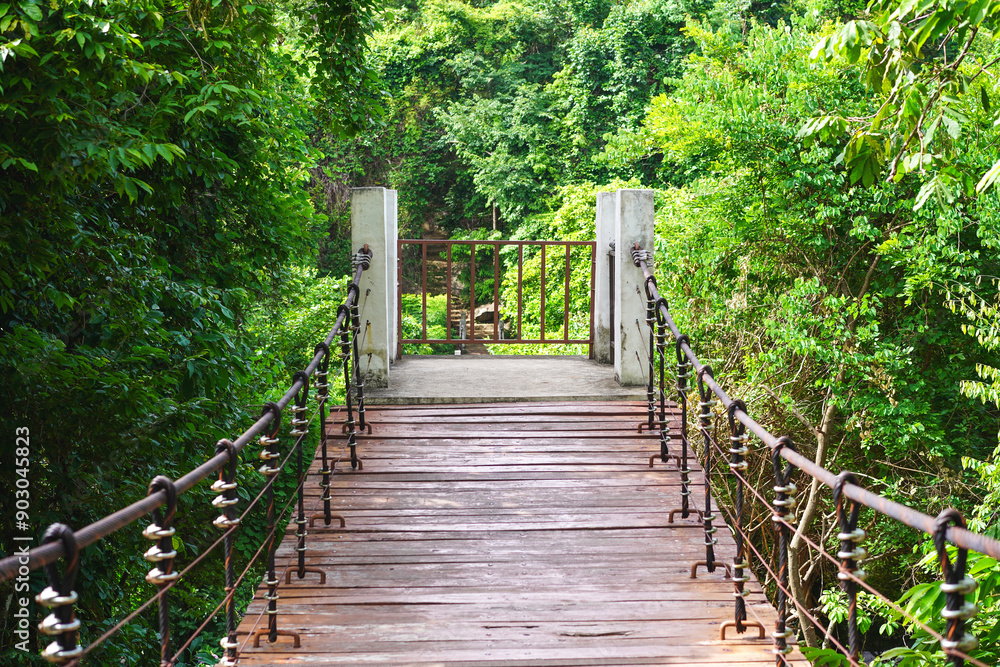 End of wooden footbridge and nature jungle. Wooden walking swing bridge, Wooden pathway in tropical forest, suspension bridge across Tat Ton Waterfall at Tat Ton National Park, Chaiyaphum. End of wooden footbridge and nature jungle. Wooden walking swing bridge, Wooden pathway in tropical forest, suspension bridge across Tat Ton Waterfall at Tat Ton National Park, Chaiyaphum.