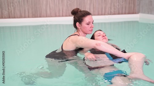 Two woman in pool. Watsu. Blue water rehabilitation massage. Aqua therapy exercise. Physio medical fitness. Sport spa relax. Swim gym class. Adult rehab physiotherapy.