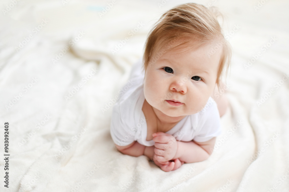 Portrait of a cute Caucasian 3-month-old baby girl during tummy time looking at the camera with the white background. Copy space. Portrait of a cute Caucasian 3-month-old baby girl during tummy time looking at the camera with the white background. Copy space.