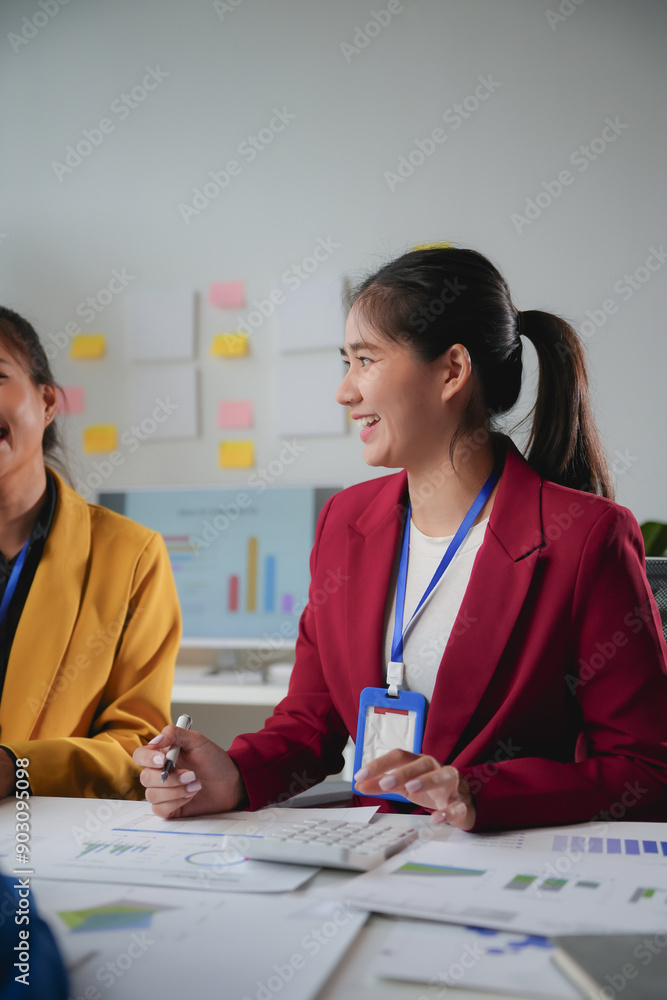 Team of young businesswomen is working together in the office, analyzing data and discussing a project Team of young businesswomen is working together in the office, analyzing data and discussing a project