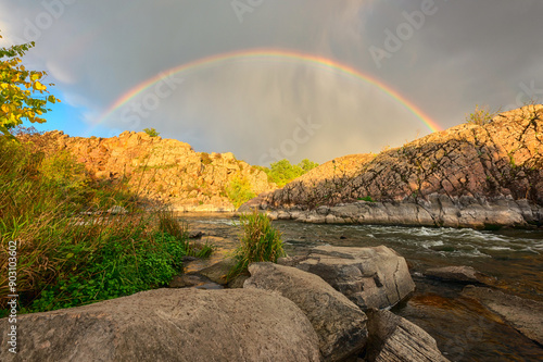 Amazing full rainbow over a scenic rocky canyon of the Southern Bug river, beautiful autumn landscape with water, rocks and sky. National park Bugski Guard, Mykolaiv region, Ukraine, travel background photo