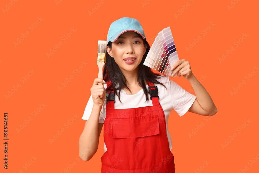 Female Asian painter with paint color palettes and brush on orange background Female Asian painter with paint color palettes and brush on orange background
