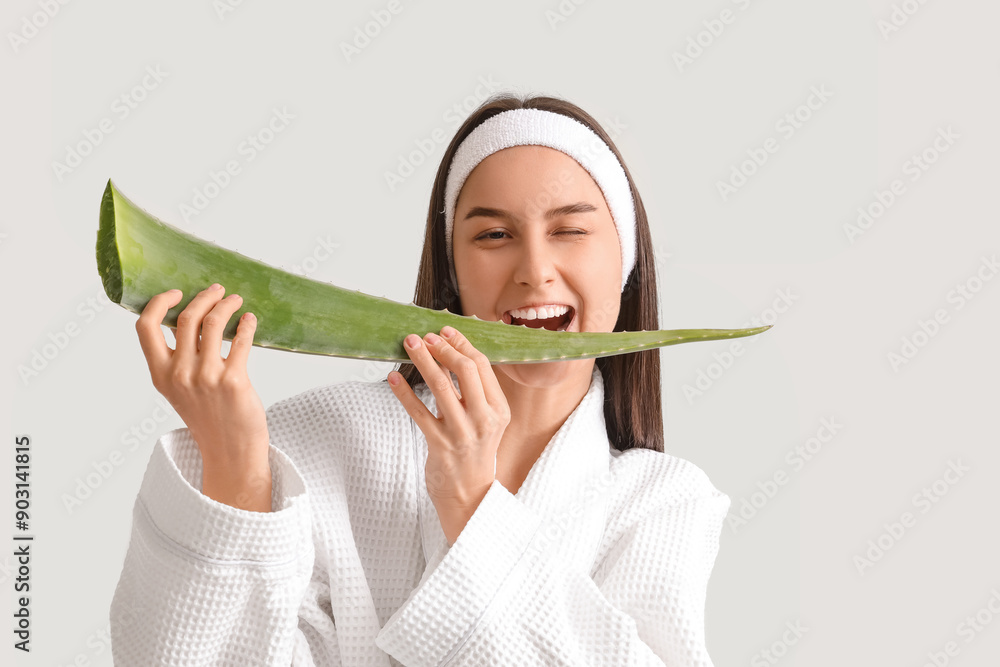 Beautiful young happy woman in bathrobe with aloe vera leaf on white background Beautiful young happy woman in bathrobe with aloe vera leaf on white background