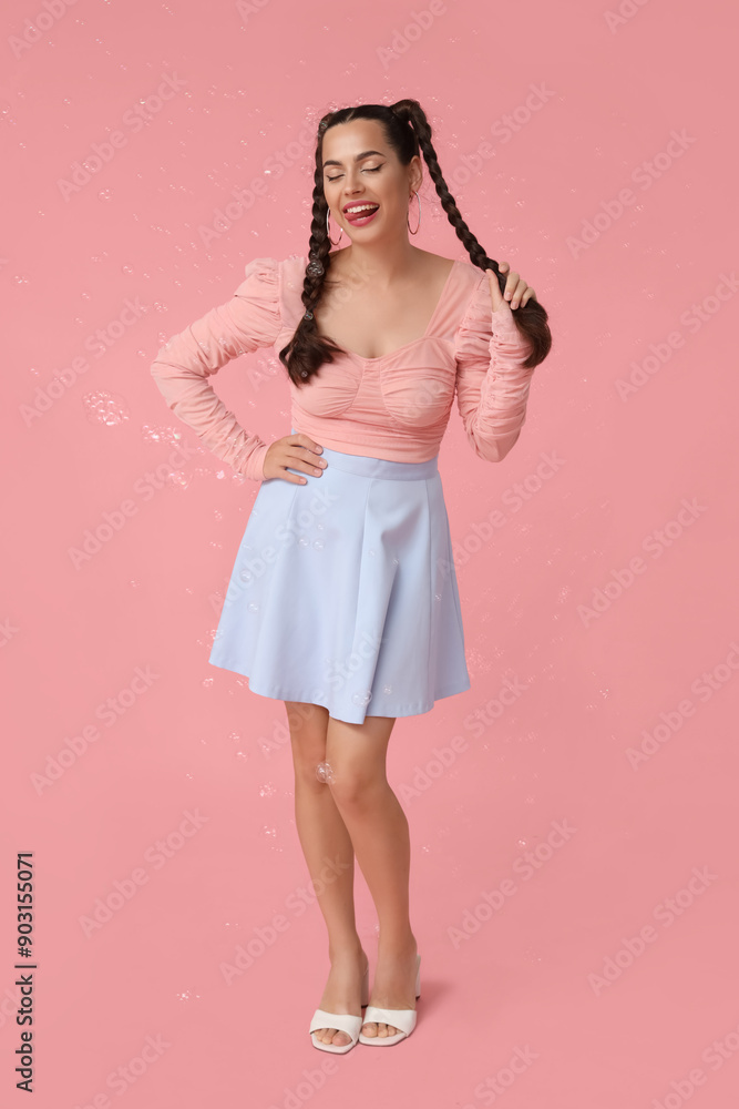 Beautiful young happy stylish woman with braids and soap bubbles on pink background Beautiful young happy stylish woman with braids and soap bubbles on pink background
