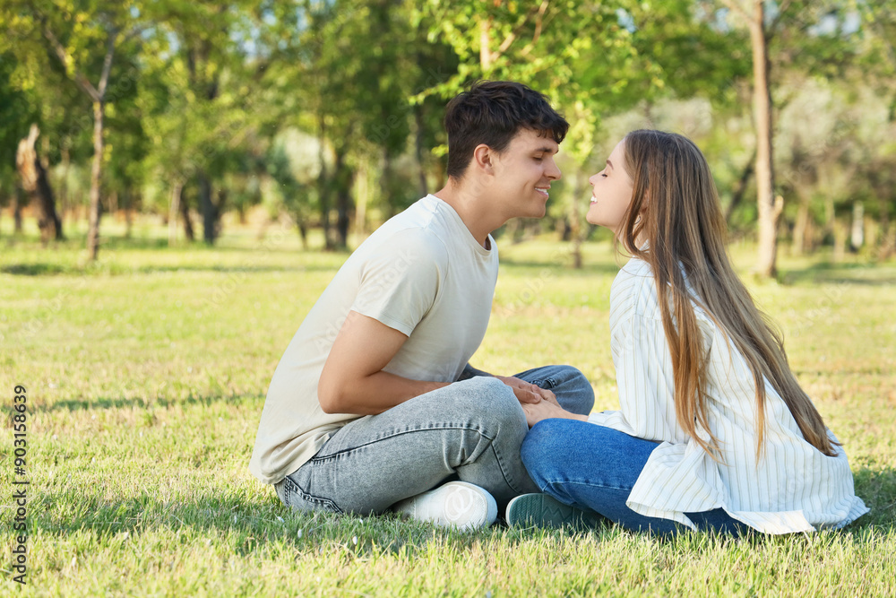 Beautiful young happy couple sitting in summer park Beautiful young happy couple sitting in summer park