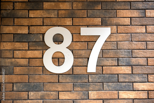 Number 87. Address sign on the brick wall. photo