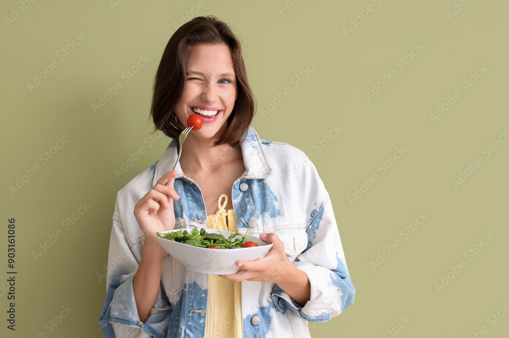 Beautiful young happy woman with bowl of fresh healthy salad on green background. Diet concept