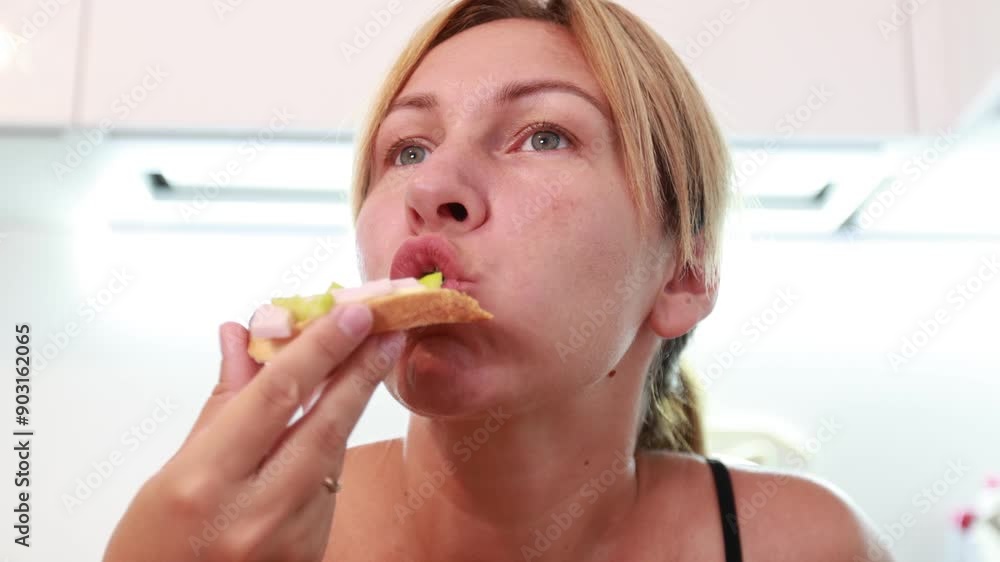 Caucasian Woman Enjoying Delicious Food While Standing in a Bright Kitchen Caucasian Woman Enjoying Delicious Food While Standing in a Bright Kitchen