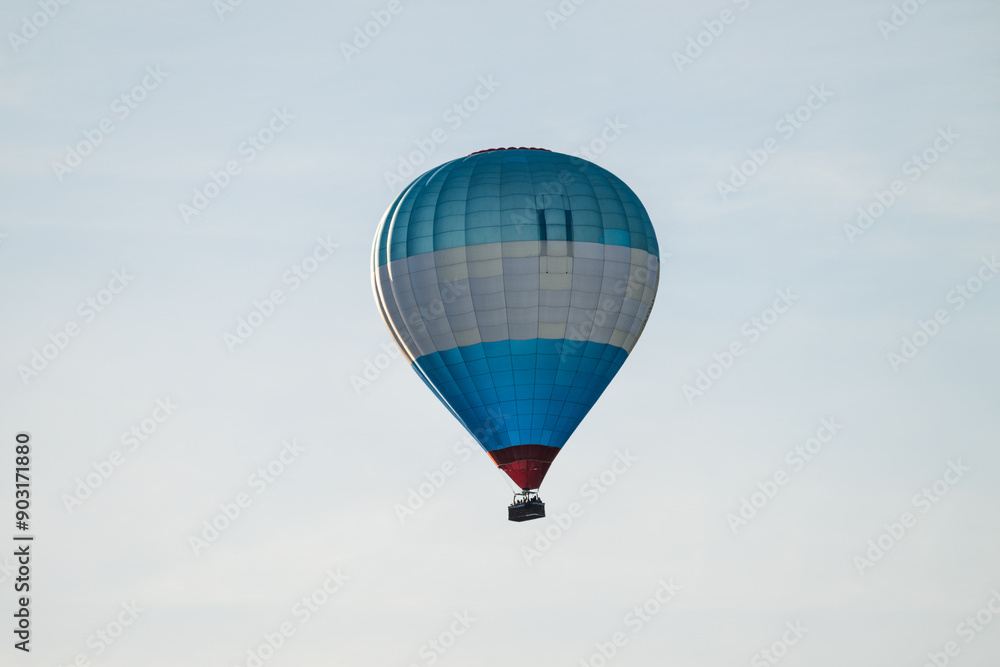 Obraz premium Blue white and red hot air balloon in evening sun.
