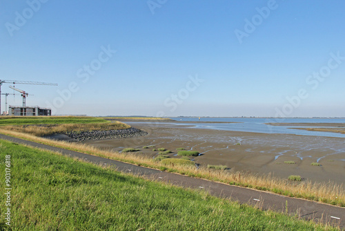 tidal mudflats with low tide in the westerschelde sea next to the seawall with apartment complexes under construction at the dutch coast in zeeland near Antwerp photo