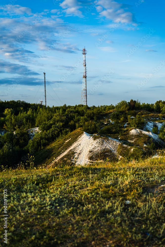 Obraz premium Telecommunications Towers Stand Tall Over Green Landscape at Dusk in Rural Area