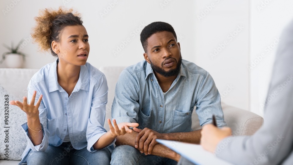 Couples Therapy Session. African American Wife Talking To Counselor Sitting On Sofa Next To Husband. Selective Focus Couples Therapy Session. African American Wife Talking To Counselor Sitting On Sofa Next To Husband. Selective Focus