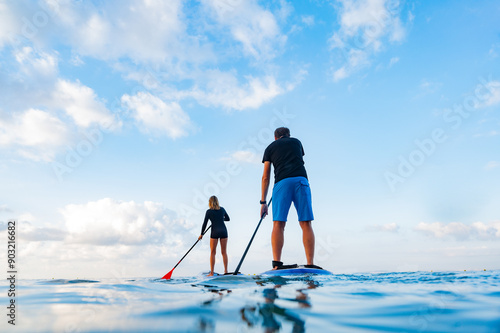 Two young men on their backs on a paddle surfboard in the sea