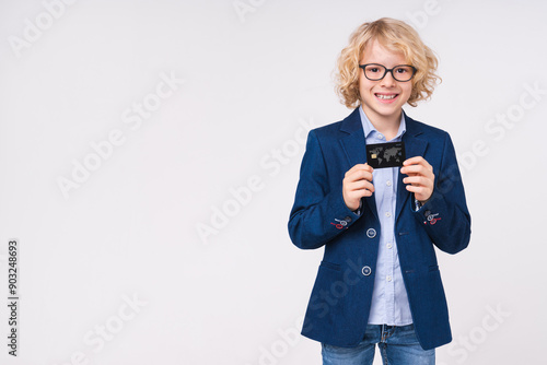 Smiling caucasian small preteen boy male child kid elementary primary middle school pupil in formal wear uniform showing demonstrate credit bank plastic card isolated on white background