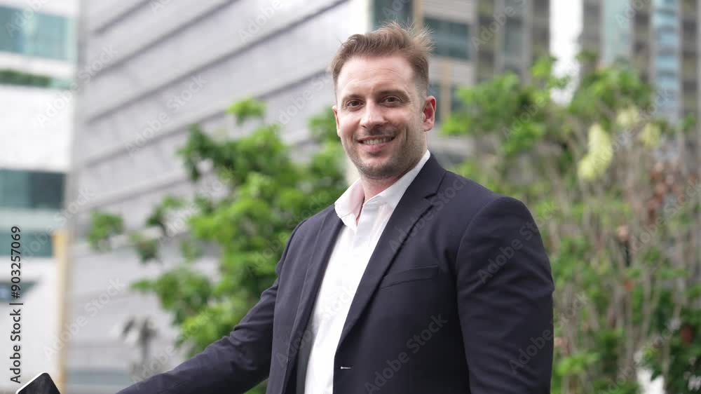 Close up of happy business man smiling and looking at camera at rooftop. Executive manager standing with confidence with skyscraper view while wear formal suit. Green environment concept. Urbane. Close up of happy business man smiling and looking at camera at rooftop. Executive manager standing with confidence with skyscraper view while wear formal suit. Green environment concept. Urbane.