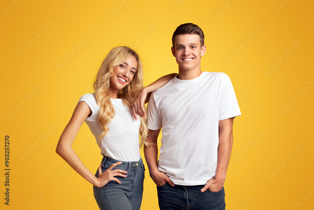 Cool millennials. Smiling guy and girl posing over yellow background, copy space Cool millennials. Smiling guy and girl posing over yellow background, copy space