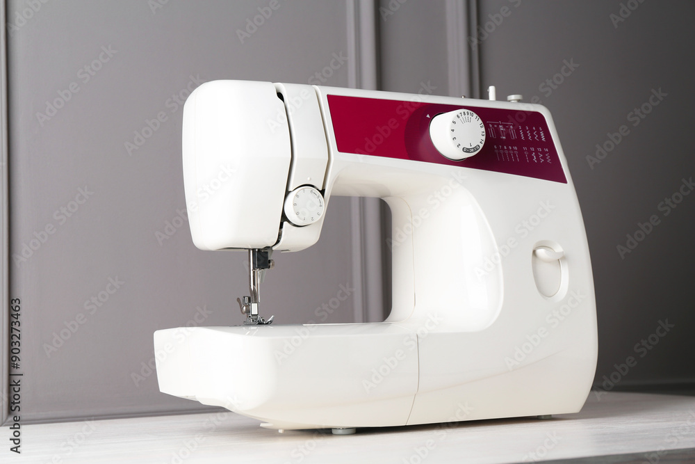Sewing machine on white wooden table near gray wall Sewing machine on white wooden table near gray wall