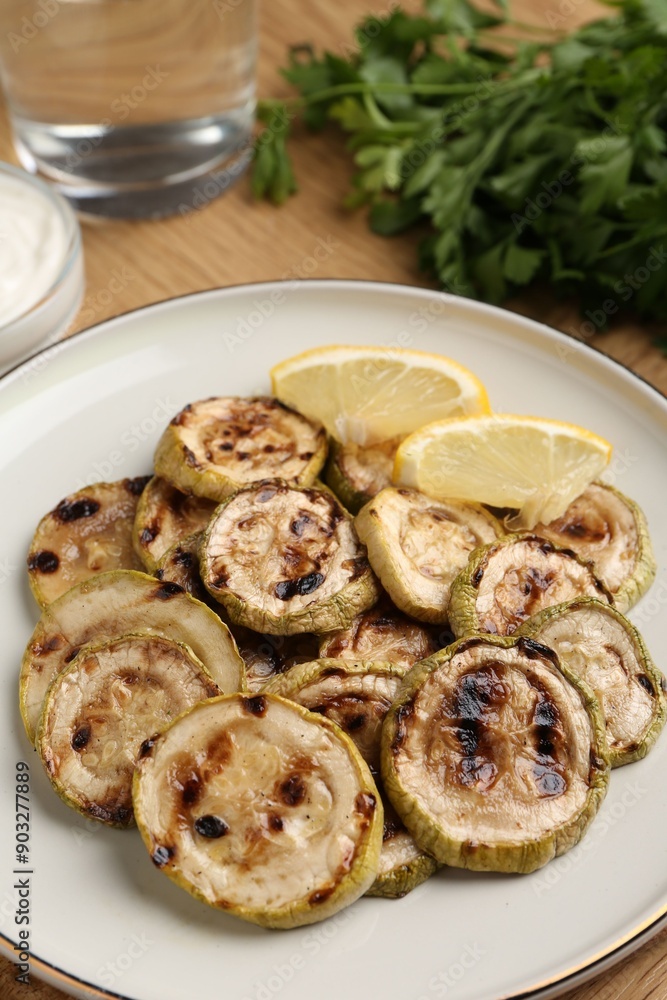 Tasty grilled courgette slices with lemon on table