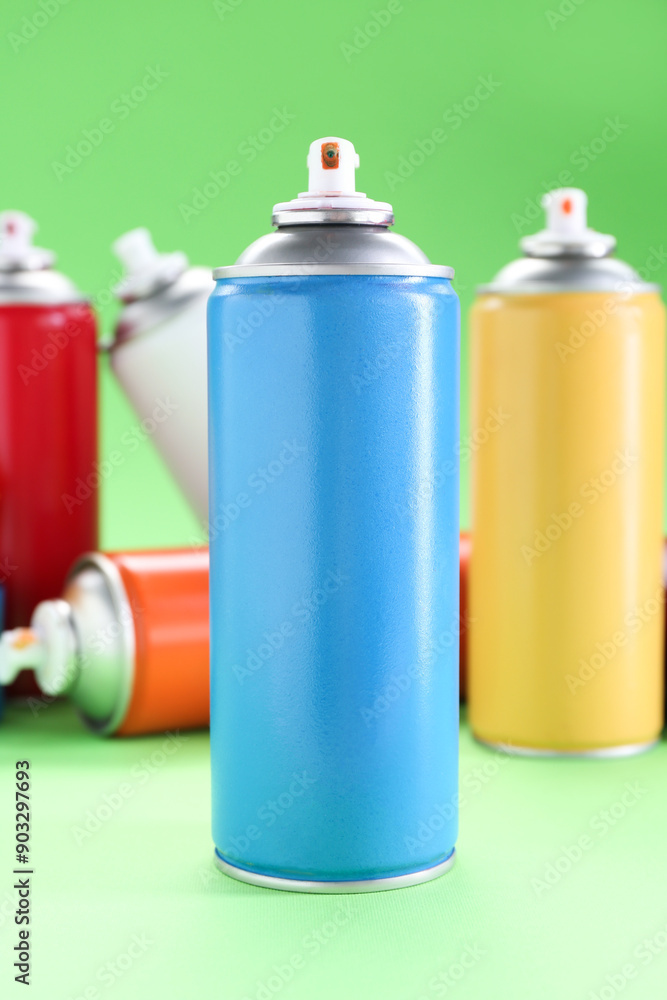 Many spray paint cans on green background, closeup Many spray paint cans on green background, closeup