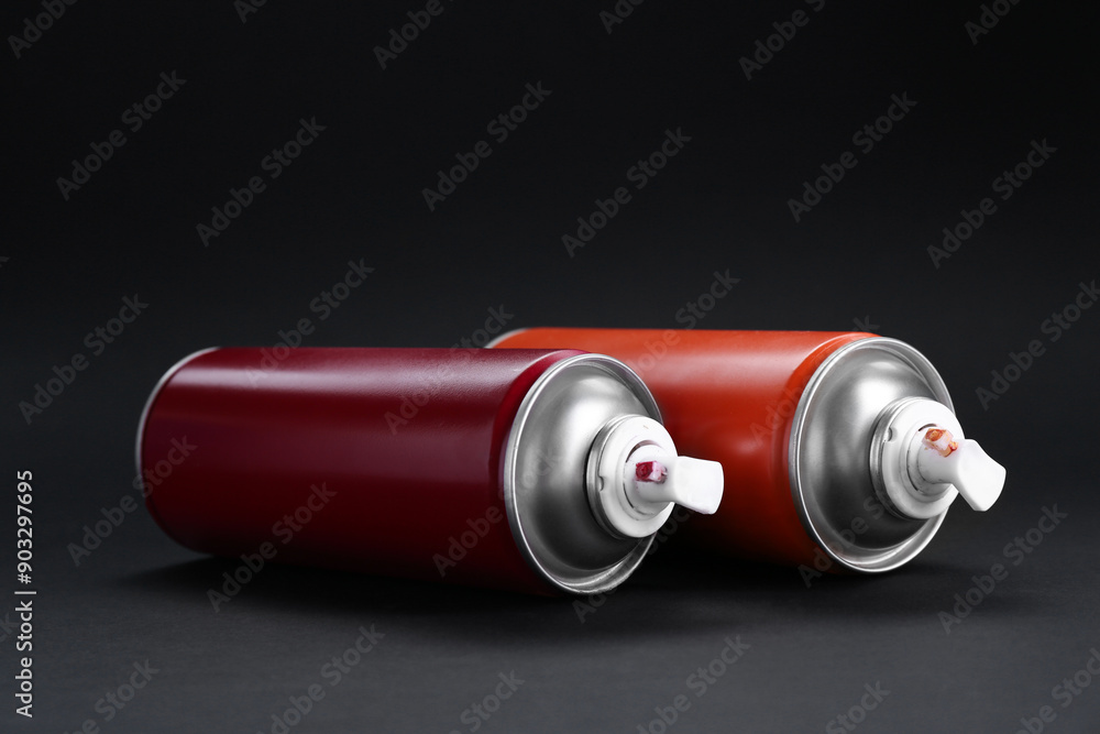 Two spray paint cans on dark gray background, closeup Two spray paint cans on dark gray background, closeup