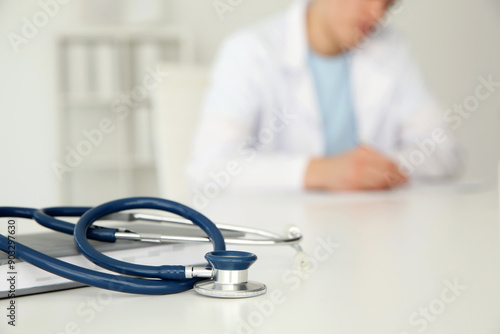 Doctor at white table in hospital, focus on medical stethoscope