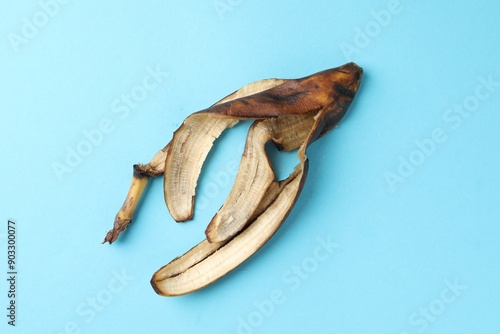 Banana peel with dark spots on light blue background, top view photo