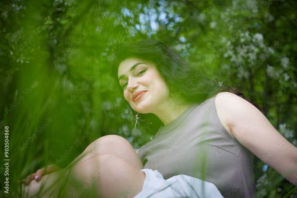 Joyous brunette woman near Blossoms of apple tree in a Spring Garden outdoors. Concept of face and body care. The scent of perfume and tenderness Joyous brunette woman near Blossoms of apple tree in a Spring Garden outdoors. Concept of face and body care. The scent of perfume and tenderness